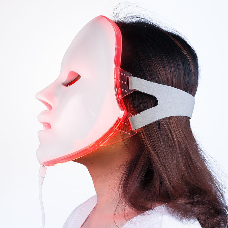 Valmirea Lumière Pro LED mask worn on face in profile, glowing red, with adjustable strap and charging cable